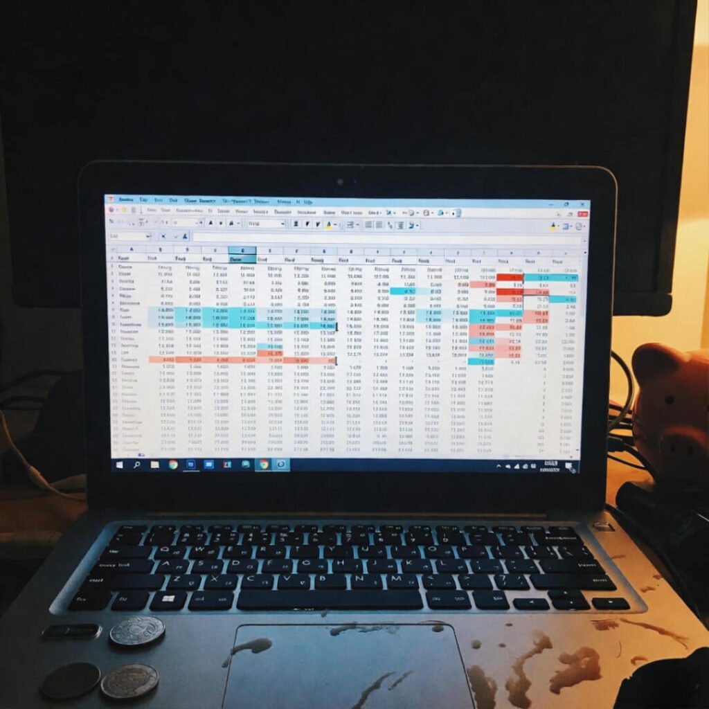 Messy budget spreadsheet on laptop with coffee stains.